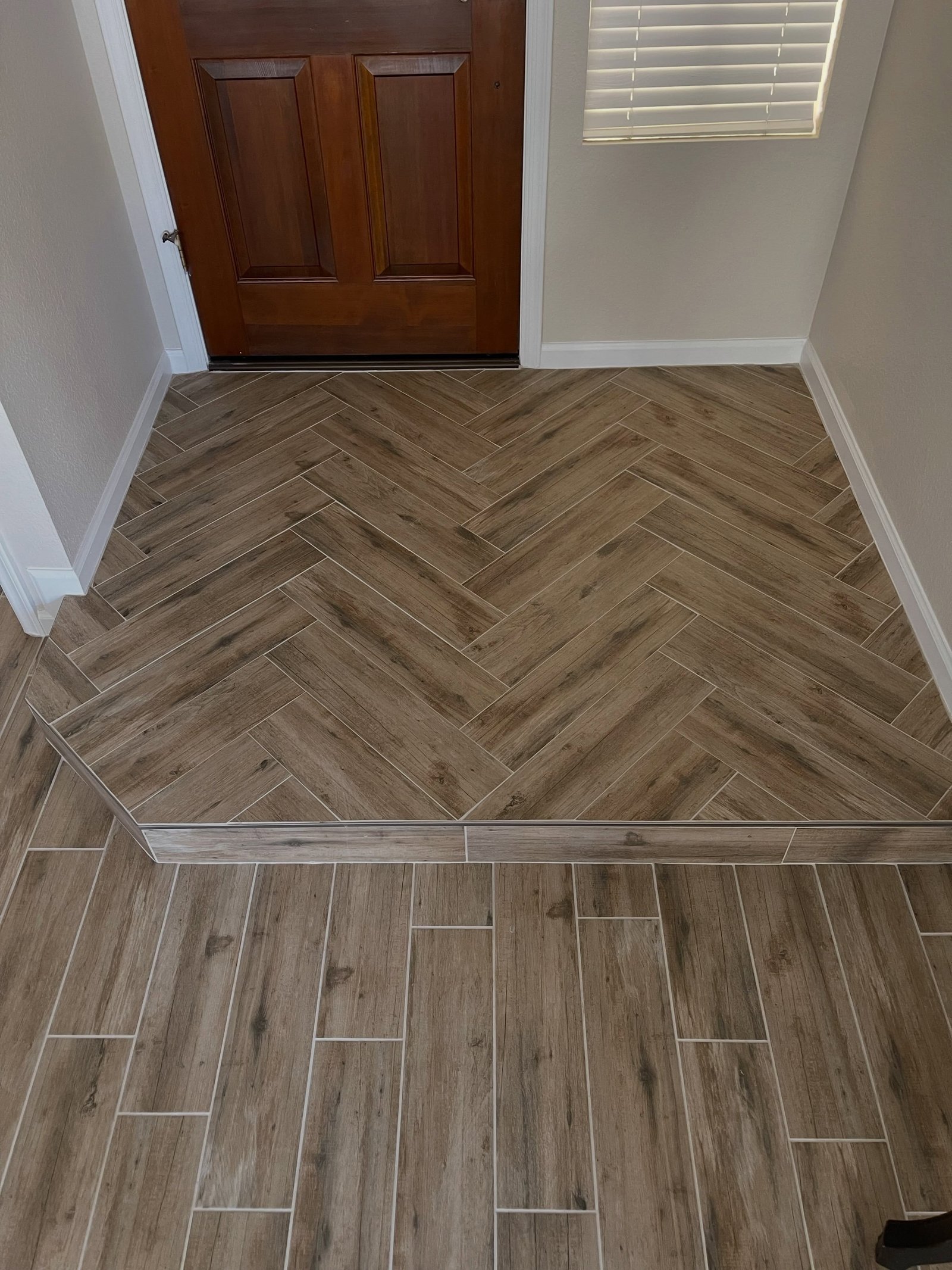 Herringbone wood-look tile entryway with straight-lay transition
